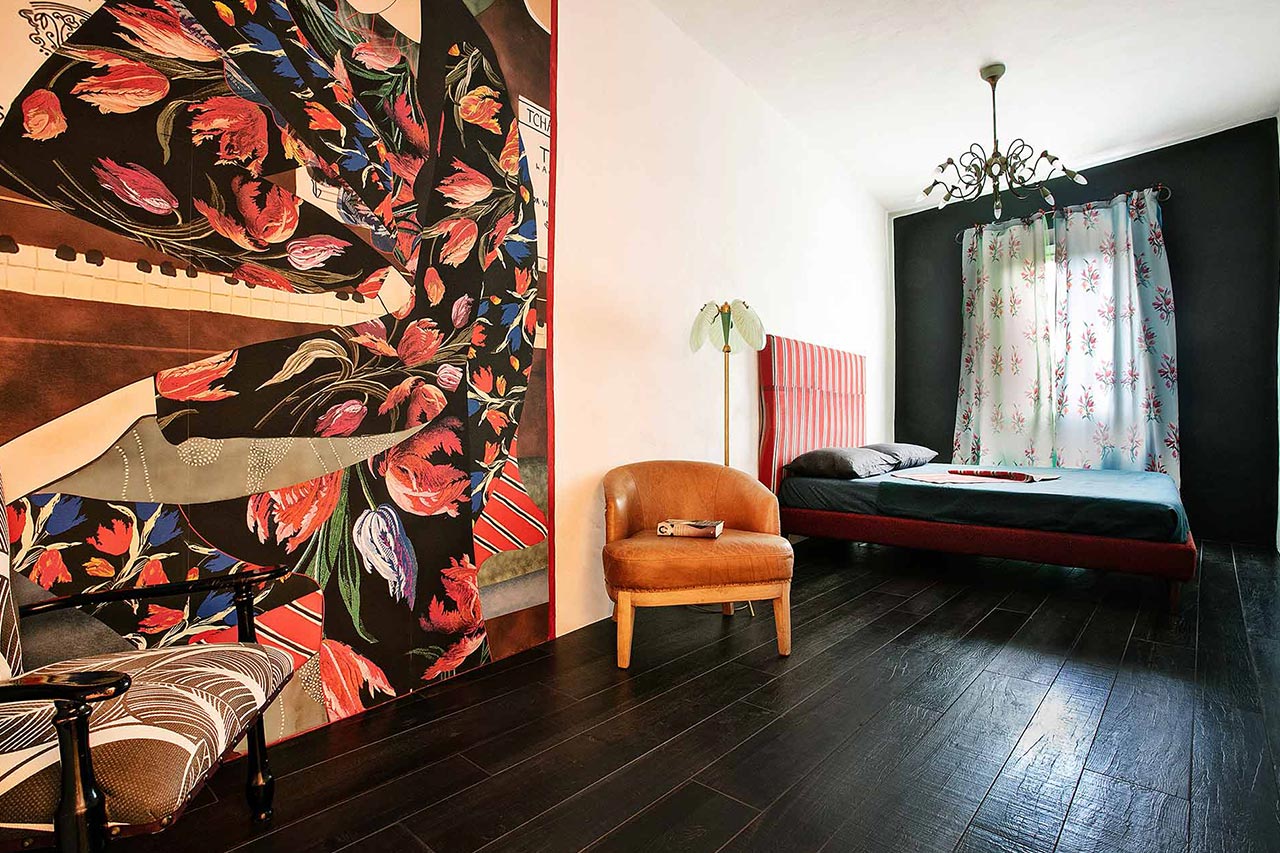 Una camera pensata per chi ama moda e arte: un corridoio di luce che corre verso i vigneti del Chianti Classico, avvolgendo l’ospite in una Toscana vibrante, fatta di colori, fantasia e libertà creativa.